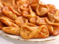 Plato de pestiños antiguos, dorados y brillantes, con un glaseado que los hace irresistibles. Perfectos para acompañar un café.