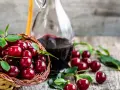 Koszyk pełen wiśni i butelka nalewki z wiśni – przepis babci. Aromatyczny trunek gotowy do degustacji.