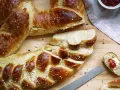 Goldbraune Neujahrsbrezel, mit Salz bestreut, auf einem Holztisch. Ein Stück ist mit Butter und Marmelade belegt. Ein tolles Neujahrsbrezel Rezept!