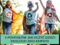 Trójka dzieci w pelerynach i maskach superbohaterów, z symbolami recyklingu na koszulkach, biegnie przez trawnik. Uczą się ekologii!