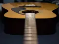 Nahaufnahme einer Westerngitarre mit Fokus auf die Saitenlage und das Griffbrett.