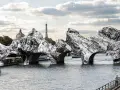 Pont de pierre transformé en rochers monumentaux, une vision audacieuse de Christo et Jeanne-Claude sur la Seine, avec la Tour Eiffel en arrière-plan.