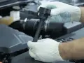 Ręce w białych rękawiczkach wymieniają cewkę zapłonową. Unikaj skutków jazdy z uszkodzoną cewką zapłonową, wymieniając ją na czas.
