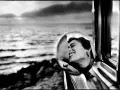 Un doux reflet dans le rétroviseur d'une voiture, une femme rit aux éclats, le regard tourné vers la mer.