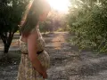 Schwanger mit zu viel Fruchtwasser, steht im Sonnenlicht unter Olivenbäumen.
