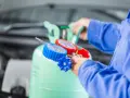 Mechanik podłącza manometry do butli z czynnikiem R32, przygotowując się do serwisu klimatyzacji samochodowej.