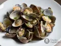 Un plato de almejas a la marinera, jugosas y recién cocinadas, con perejil picado.
