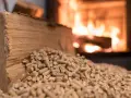 Leña y pellets junto a una estufa encendida. Precaución con los peligros de las estufas de pellets y el almacenamiento seguro.