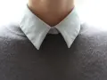 Gros plan sur un col froncé blanc sur un pull gris.