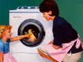Mutter und Kind vor der ersten Waschmaschine. Das kleine Mädchen hilft beim Einräumen der Wäsche.