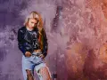 Blondynka w skórzanej kurtce i podartych dżinsach, z siatką na nogach, emanuje **grunge**'owym klimatem.