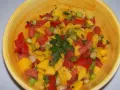 Bunte Mango Salsa mit Tomaten, Frühlingszwiebeln und Petersilie in einer gelben Schüssel.