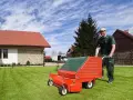 Mężczyzna z wertykulatorem na trawniku. Wertykulacja latem to klucz do zdrowej, zielonej murawy.