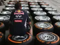 Mechanik w stroju Red Bulla siedzi wśród rzędów opon F1.