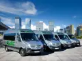 Rząd srebrnych busów Contbus na tle nowoczesnych wieżowców i błękitnego nieba.