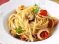 Tallarines con gambas al ajillo, mejillones y calamares, salpicados con perejil fresco y trocitos de tomate.