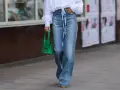 Mujer con vaqueros anchos, talla 30 pantalón equivalencia España, y bolso verde.