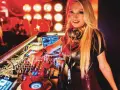 Une dj femme connue aux platines, mixant dans une ambiance club avec des lumières rouges.