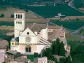 Basilica of Saint Francis of Assisi, a stunning example of Italian monasteries, with its iconic bell tower and rose window, nestled in a verdant landscape.