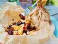 Fruchtiger Nachtisch vom Grill: Apfelstücke, Blaubeeren und Bananen mit Schokoladensauce, serviert in Papier.