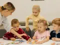 Nauczycielka pomaga dzieciom układać obrazki. Czy przedszkole może wypisać dziecko? Dzieci uczą się przez zabawę.