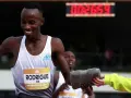 Atleta sonriente recibe toalla en una carrera de Madrid vintage. El marcador digital muestra 00:26:59.