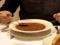Persona prueba una cucharada de una humeante olla podrida, un plato reconfortante y tradicional.