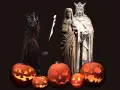 Skrämmande pumpor lyser upp mörkret inför **halloween datum**. En figur med horn och fackla står bredvid statyer av ett kungapar.