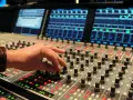 Hand am Mischpult, das an die Erfindung von Autotune erinnert. Tontechniker regelt Regler.