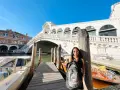 Una splendida giornata a Venezia, con la giovane donna che posa con il suo zaino davanti al Ponte di Rialto e ai taxi d'acqua.