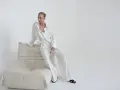 Elegancka kobieta w pasiastym komplecie, uosobienie quiet luxury, siedzi na kremowej sofie.