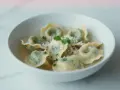 Pyszne tortellini in brodo przepis. Zielone pierożki w bulionie, posypane parmezanem i natką pietruszki.