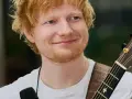 Ed Sheeran z gitarą, uśmiechnięty, w białej koszulce.
