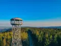 Metalowa jagodna wieża widokowa wznosi się nad gęstym lasem iglastym, oferując zapierającą dech w piersiach panoramę.