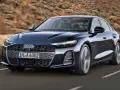 Elegancki, ciemnogranatowy Audi A6 sunie po drodze, z kierowcą w okularach za kierownicą.