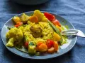 Ein Teller mit gelbem Reis, Blumenkohl, Karotten, Paprika und Erbsen. Ein köstliches Curry Geschnetzeltes, bereit zum Genießen.
