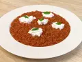 Un invitante risotto al pomodoro, arricchito da ciuffi di ricotta fresca e basilico, pronto per essere gustato.