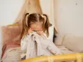 Kleines Kind mit Zöpfen versteckt sich unter einer Decke, weil es Angst vor Monstern hat.