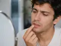 Hombre se toca los labios con preocupación, preguntándose porque se queman los labios.