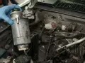 Ręka w niebieskiej rękawiczce wyjmuje filtr paliwa. Pamiętaj, co ile wymieniać filtr paliwa, by silnik działał sprawnie.