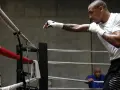 Un boxeur s'entraîne en shadow boxing dans un ring, concentré sur ses mouvements.