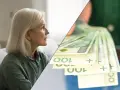 Zamyślona kobieta i stos banknotów 100 zł. Zastanawia się, ile wynosi renta wdowia.