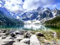 Morskie Oko, jedne z najpiękniejszych gór w Polsce, otoczone ośnieżonymi szczytami i zielonymi lasami, odbija się w krystalicznie czystej wodzie.