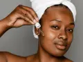 A woman applies a serum with peptides for acne, a step in her skincare routine.