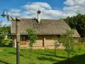 Drewniany dom z kamienną podmurówką i gontowym dachem, otoczony zielenią. To malownicze grunty rolne zabudowane, gdzie tradycja spotyka się z naturą.