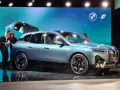 Jasnoniebieski elektryczny SUV BMW iX z otwartą klapą bagażnika na scenie.