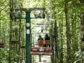 La funivia Monte Amiata trasporta due persone e una mountain bike attraverso un bosco lussureggiante.