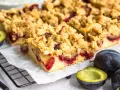 Saftiger Zwetschgenkuchen mit Streuseln, frisch gebacken und bereit zum Genießen. Daneben liegen frische Zwetschgen.