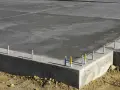 Dalle de béton fraîchement coulée, montrant la base d'une fondation et l'épaisseur de la semelle en béton.
