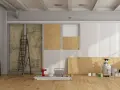 Chantier de rénovation avec panneaux de bois, échelle, outils et pots de peinture.